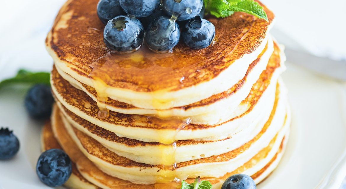 Homemade baked ricotta pancakes with fresh berries on white wooden table